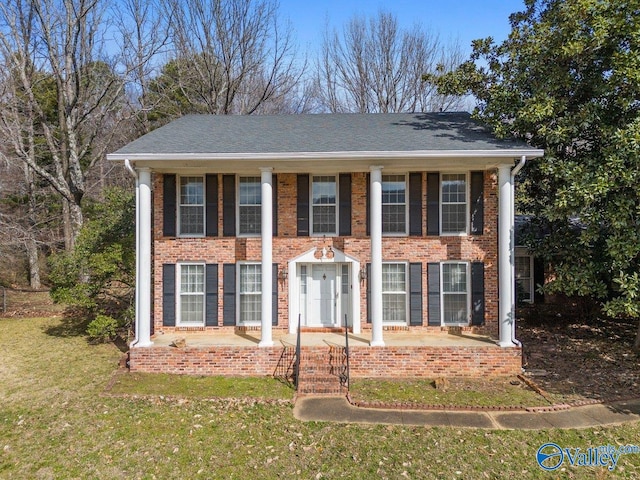 neoclassical home featuring a front yard and brick siding