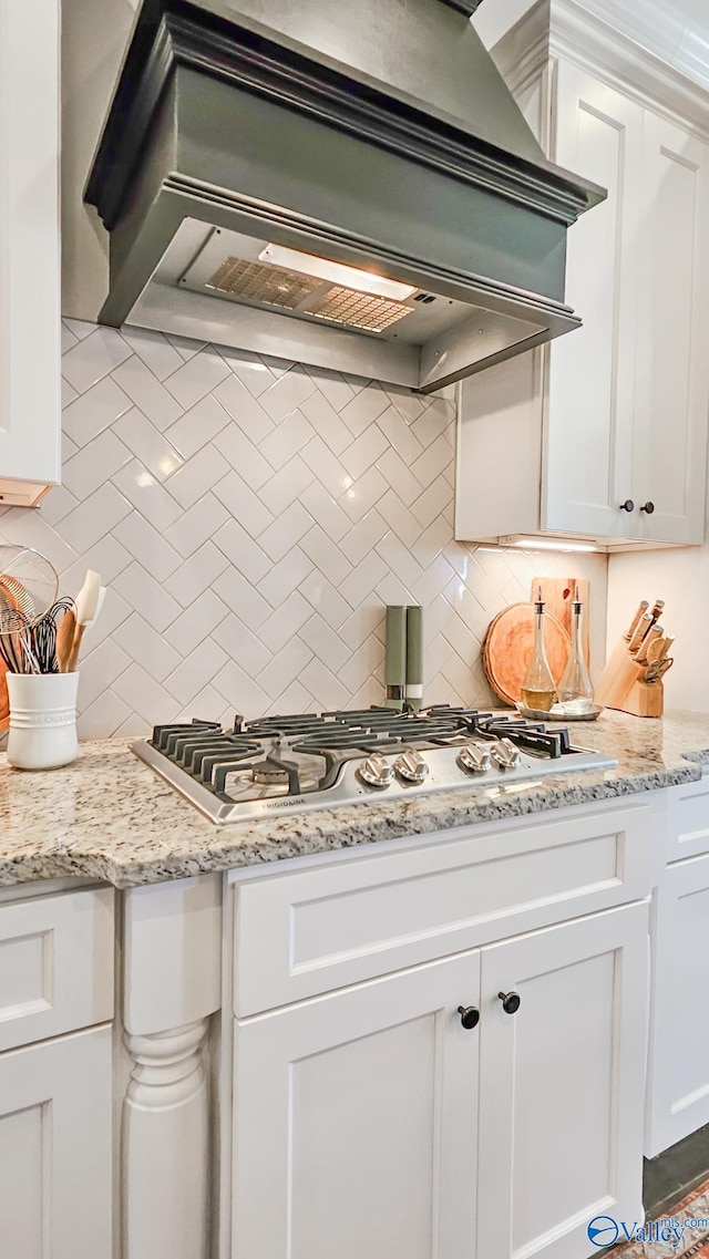 kitchen featuring tasteful backsplash, custom exhaust hood, stainless steel gas stovetop, and white cabinets