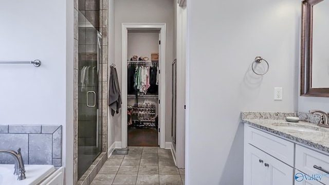 full bath with a walk in closet, vanity, a shower stall, and tile patterned flooring