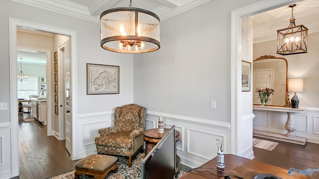 sitting room featuring crown molding, a chandelier, a wainscoted wall, hardwood / wood-style floors, and a decorative wall