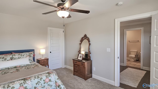 bedroom with baseboards, light colored carpet, ceiling fan, and ensuite bathroom