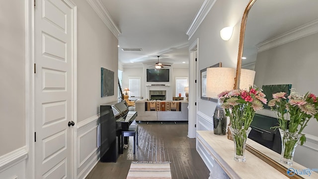 hall with visible vents, ornamental molding, wainscoting, dark wood-style floors, and a decorative wall