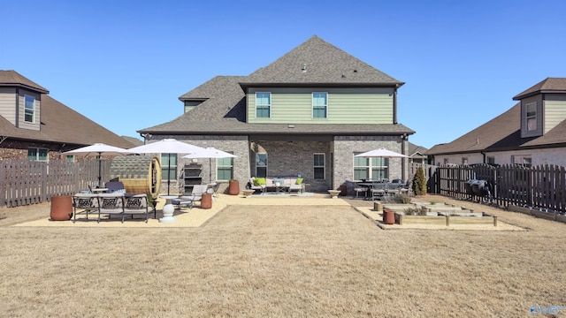 rear view of property featuring a patio, a fenced backyard, a yard, a shingled roof, and brick siding