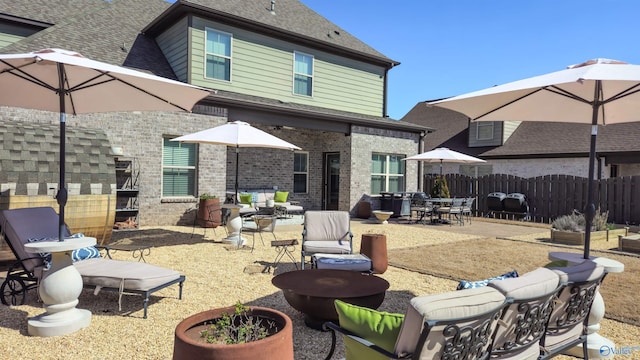 back of property featuring a patio, fence, a fire pit, roof with shingles, and brick siding