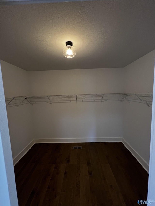 walk in closet with dark hardwood / wood-style flooring