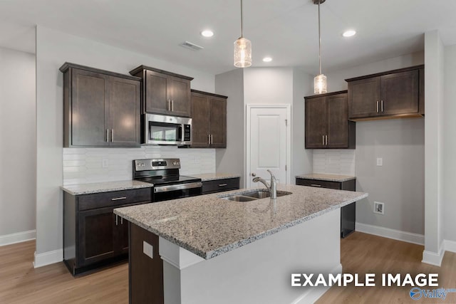 kitchen with light stone countertops, decorative backsplash, stainless steel appliances, sink, and decorative light fixtures