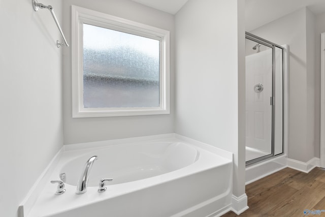 bathroom featuring wood-type flooring and shower with separate bathtub