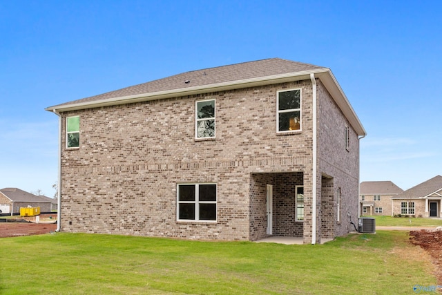 rear view of property featuring a yard and cooling unit