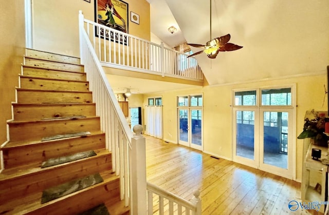 staircase featuring ceiling fan, a high ceiling, and wood-type flooring