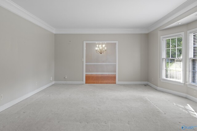 spare room featuring ornamental molding, light carpet, and a chandelier