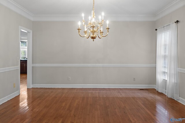 unfurnished room with hardwood / wood-style floors, an inviting chandelier, and ornamental molding