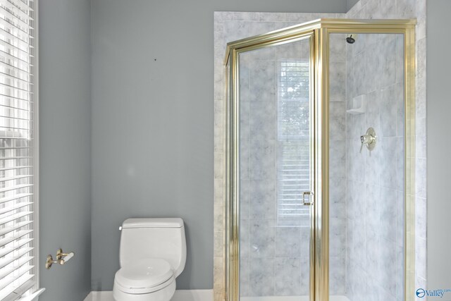 bathroom with a shower with door, plenty of natural light, and toilet