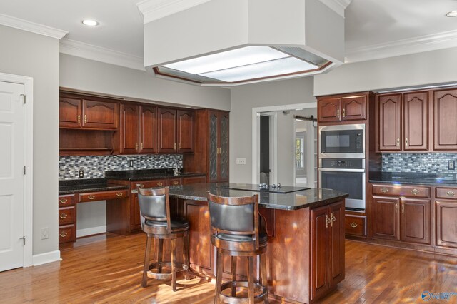 kitchen featuring crown molding, a kitchen island, wood-type flooring, and appliances with stainless steel finishes