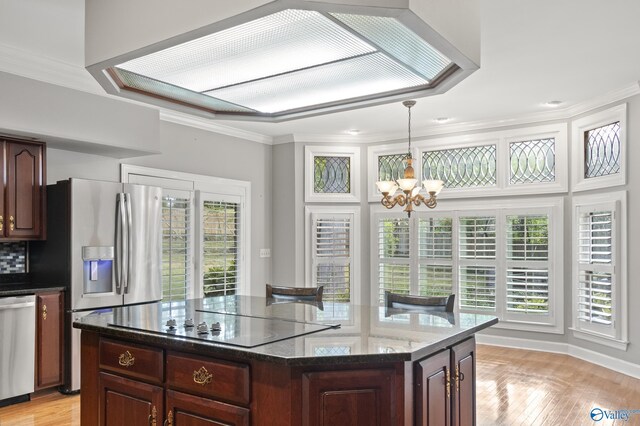 kitchen with a center island, stainless steel appliances, light hardwood / wood-style floors, a notable chandelier, and pendant lighting