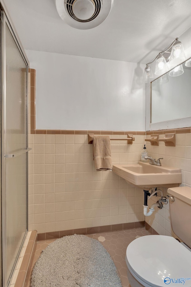 411 Darby Ave, Sheffield, AL 35660 - bathroom with a stall shower, a wainscoted wall, toilet, a sink, and tile walls