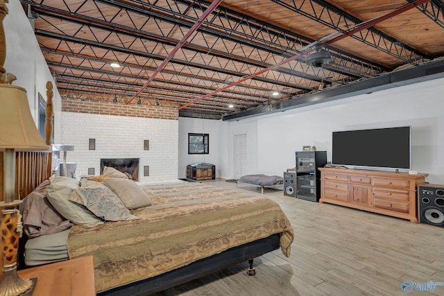 411 Darby Ave, Sheffield, AL 35660 - bedroom with a towering ceiling, wood finished floors, a brick fireplace, and brick wall