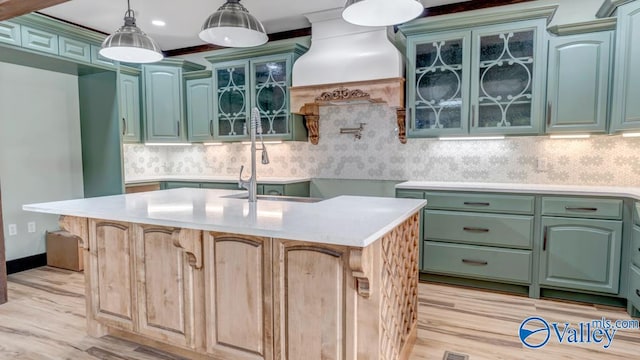 kitchen with decorative backsplash, light hardwood / wood-style flooring, and an island with sink