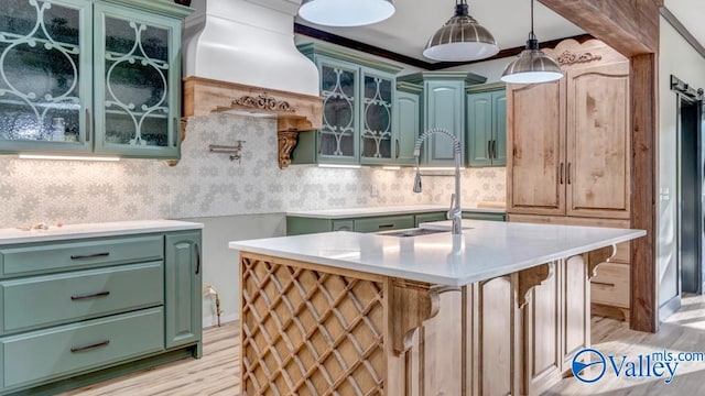 kitchen featuring light hardwood / wood-style flooring, decorative backsplash, a center island with sink, and custom range hood