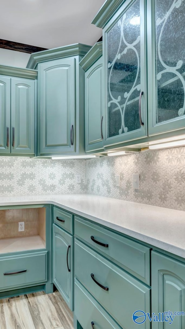 kitchen with light hardwood / wood-style flooring, green cabinetry, and backsplash