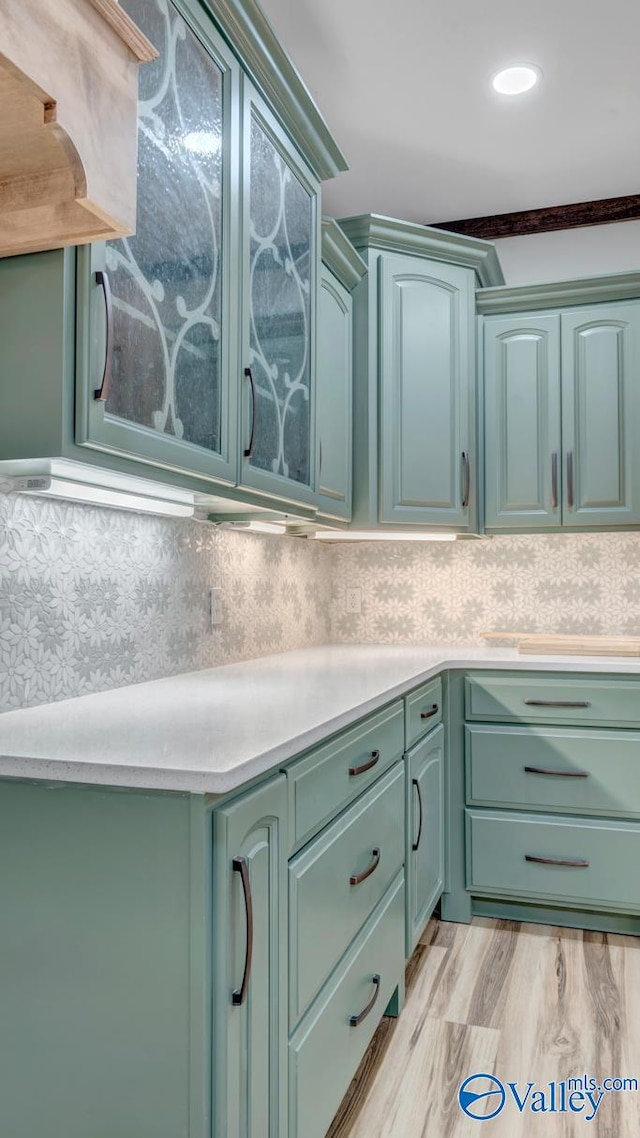 kitchen with light hardwood / wood-style floors, green cabinets, premium range hood, and backsplash