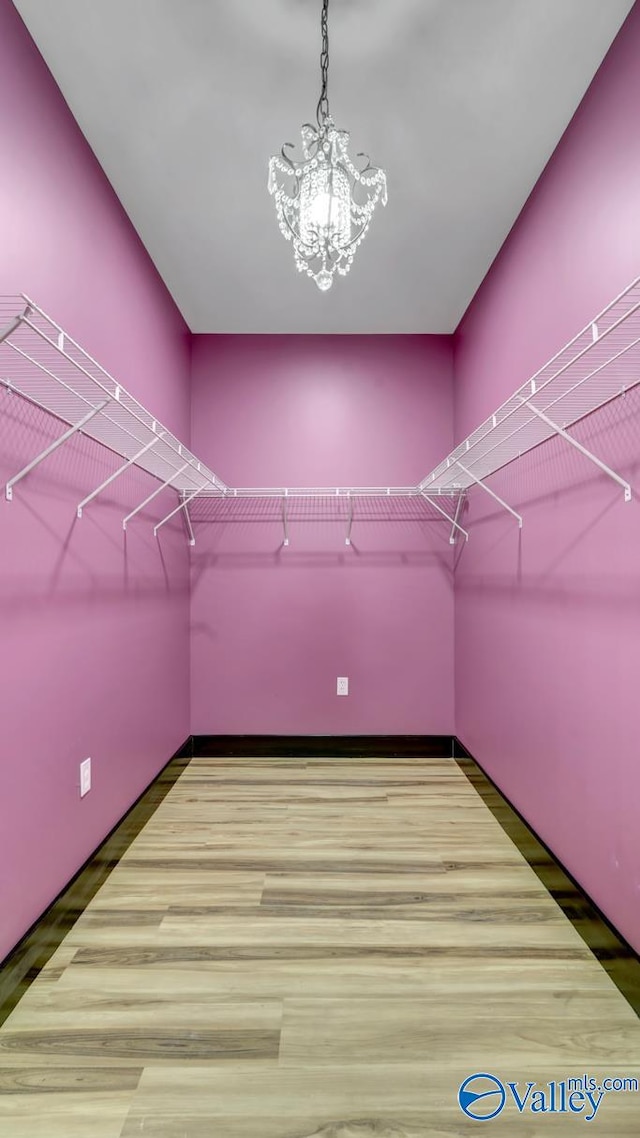 walk in closet featuring a chandelier and light wood-type flooring