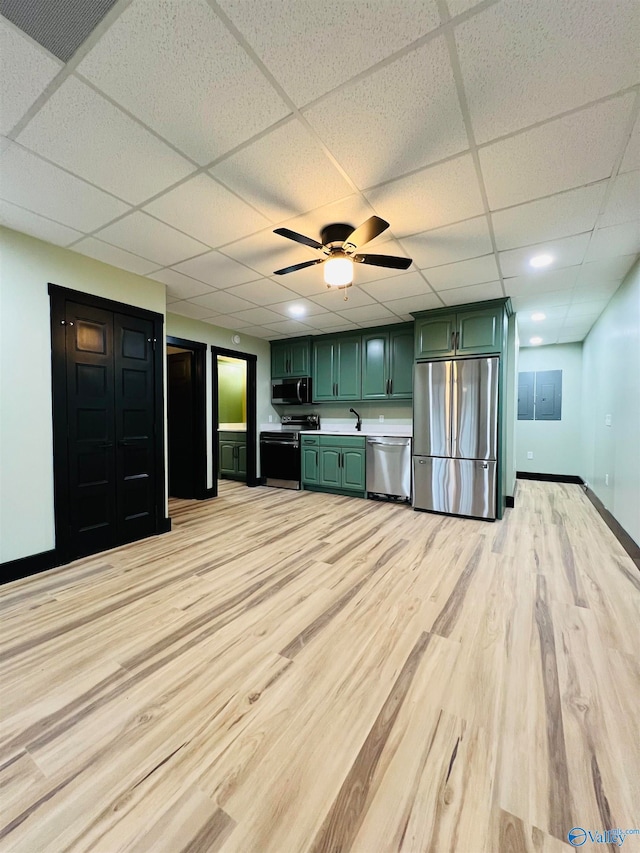 unfurnished living room featuring sink, light wood-type flooring, ceiling fan, and a drop ceiling