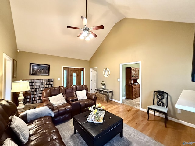 living room featuring light wood-style flooring, high vaulted ceiling, baseboards, and ceiling fan