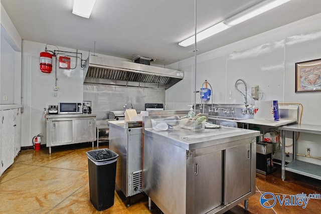 kitchen featuring range hood, concrete floors, and stainless steel counters