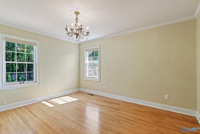 empty room with crown molding, a chandelier, and light wood-type flooring