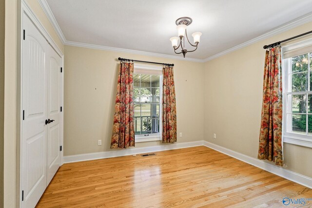 spare room with light hardwood / wood-style flooring, crown molding, an inviting chandelier, and plenty of natural light