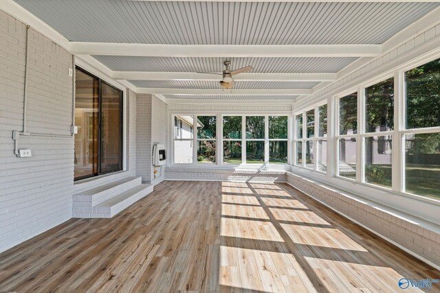 unfurnished sunroom featuring beamed ceiling, a wealth of natural light, and ceiling fan