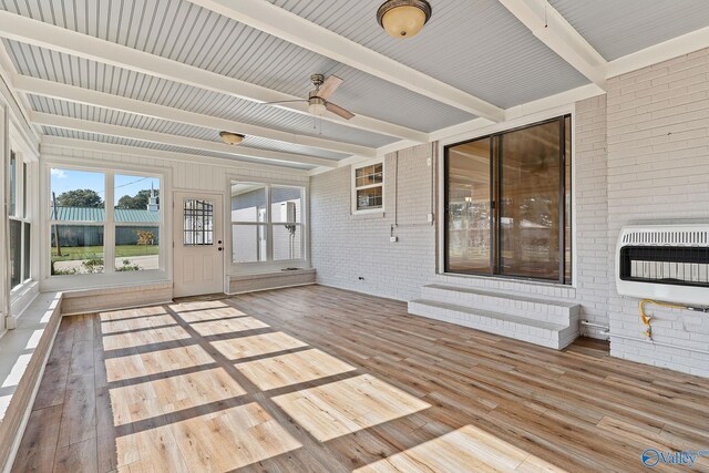 unfurnished sunroom featuring ceiling fan, beamed ceiling, and heating unit