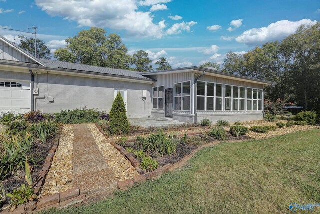 back of property featuring a garage, a sunroom, and a yard