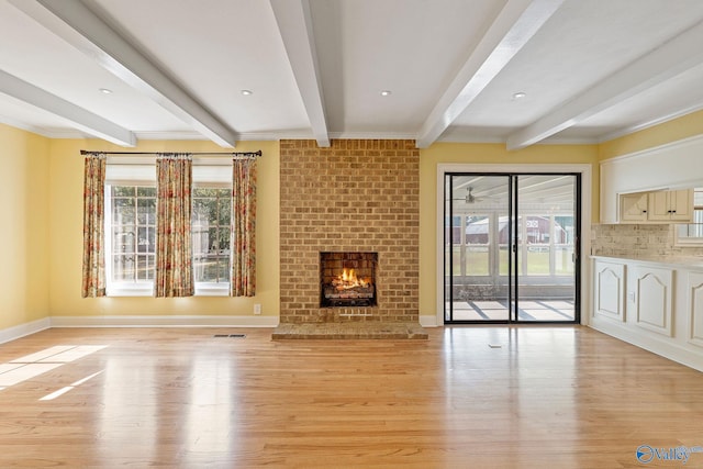 unfurnished living room featuring beamed ceiling, light hardwood / wood-style flooring, and a brick fireplace