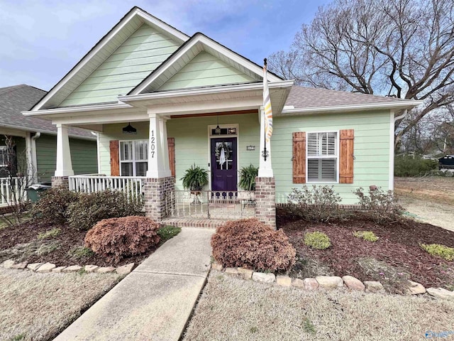 craftsman inspired home with covered porch and roof with shingles