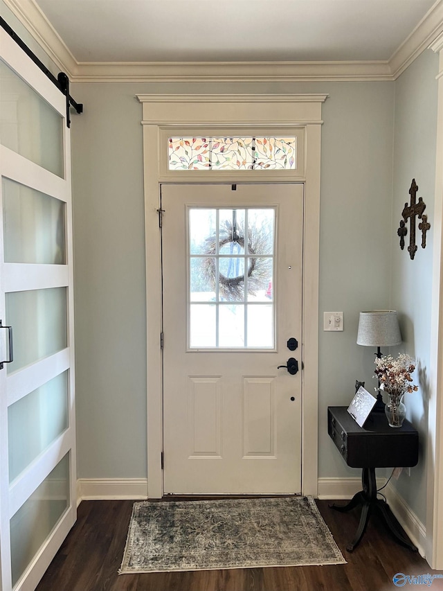 foyer featuring ornamental molding, a barn door, dark wood finished floors, and baseboards