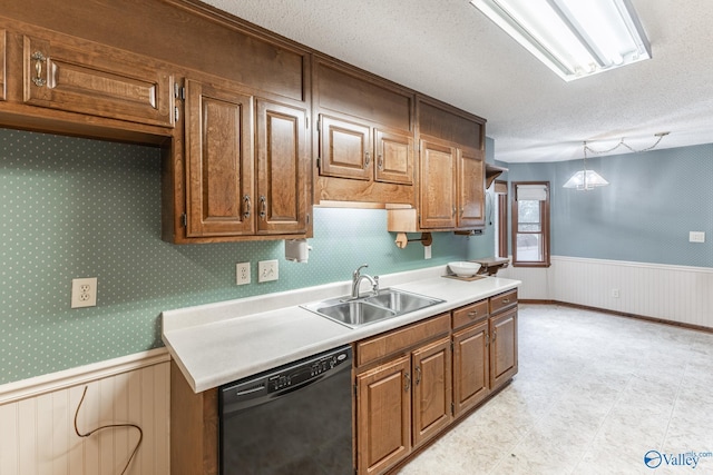 kitchen with a sink, a textured ceiling, black dishwasher, wainscoting, and light countertops