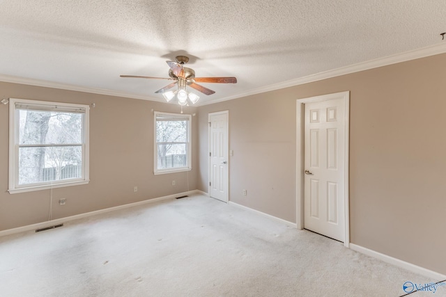 unfurnished bedroom featuring baseboards, visible vents, a textured ceiling, crown molding, and light carpet