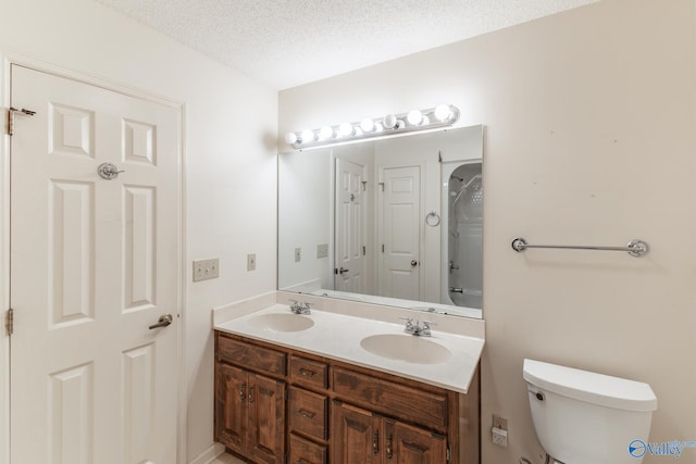 bathroom featuring double vanity, a textured ceiling, toilet, and a sink