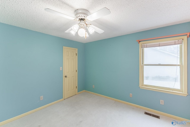 empty room with visible vents, a ceiling fan, a textured ceiling, carpet floors, and baseboards