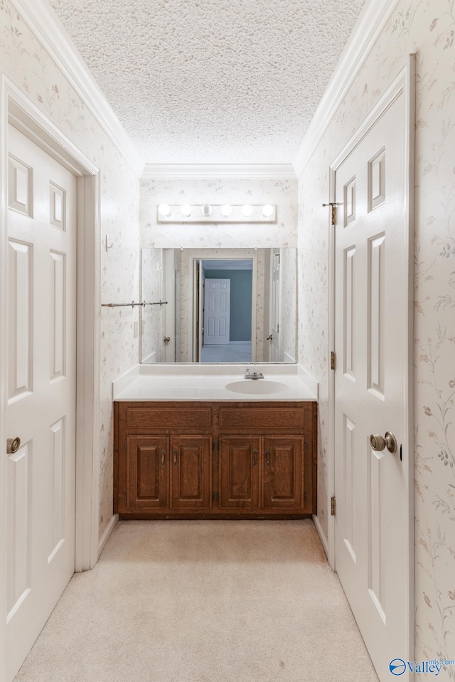 bathroom featuring wallpapered walls, crown molding, vanity, and a textured ceiling