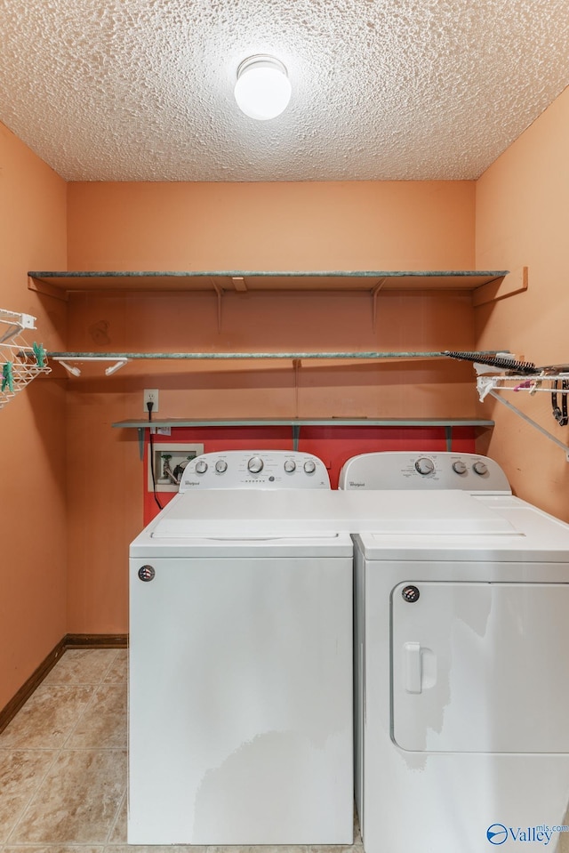 clothes washing area with light tile patterned floors, laundry area, washing machine and dryer, and a textured ceiling