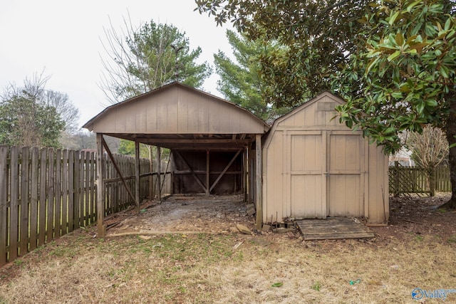 view of shed with a carport and a fenced backyard