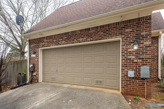 garage with concrete driveway and fence