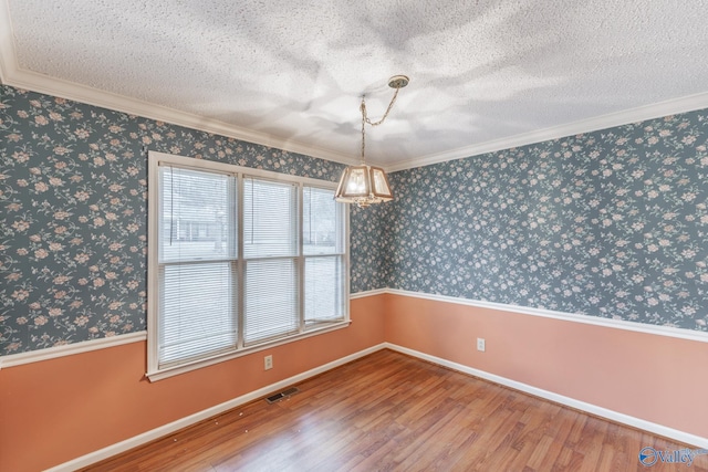 unfurnished dining area featuring visible vents, a textured ceiling, wood finished floors, and wallpapered walls