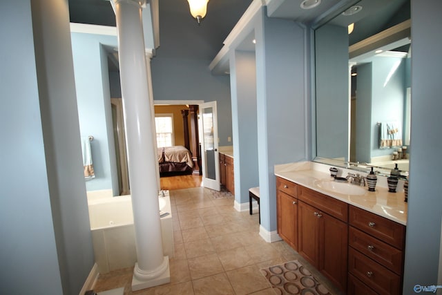 bathroom with a tub, tile patterned floors, vanity, and ornate columns