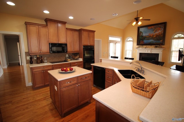 kitchen with a kitchen island, dark hardwood / wood-style floors, black appliances, sink, and kitchen peninsula