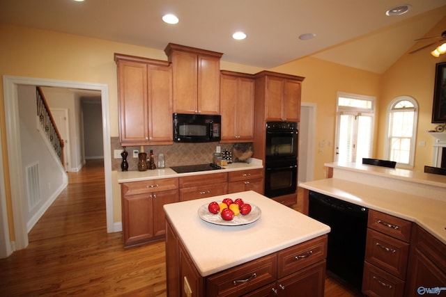 kitchen with a kitchen island, hardwood / wood-style floors, decorative backsplash, ceiling fan, and black appliances