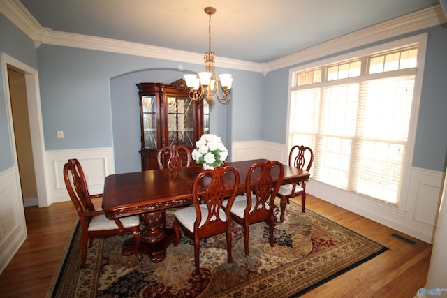 dining area with an inviting chandelier, ornamental molding, and hardwood / wood-style floors