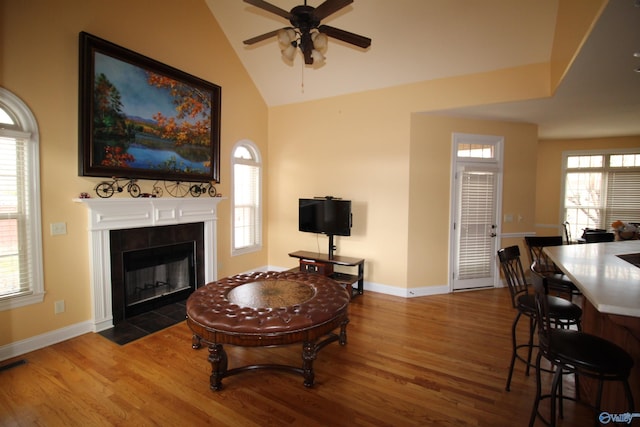 living room with a healthy amount of sunlight, dark hardwood / wood-style flooring, and a tiled fireplace